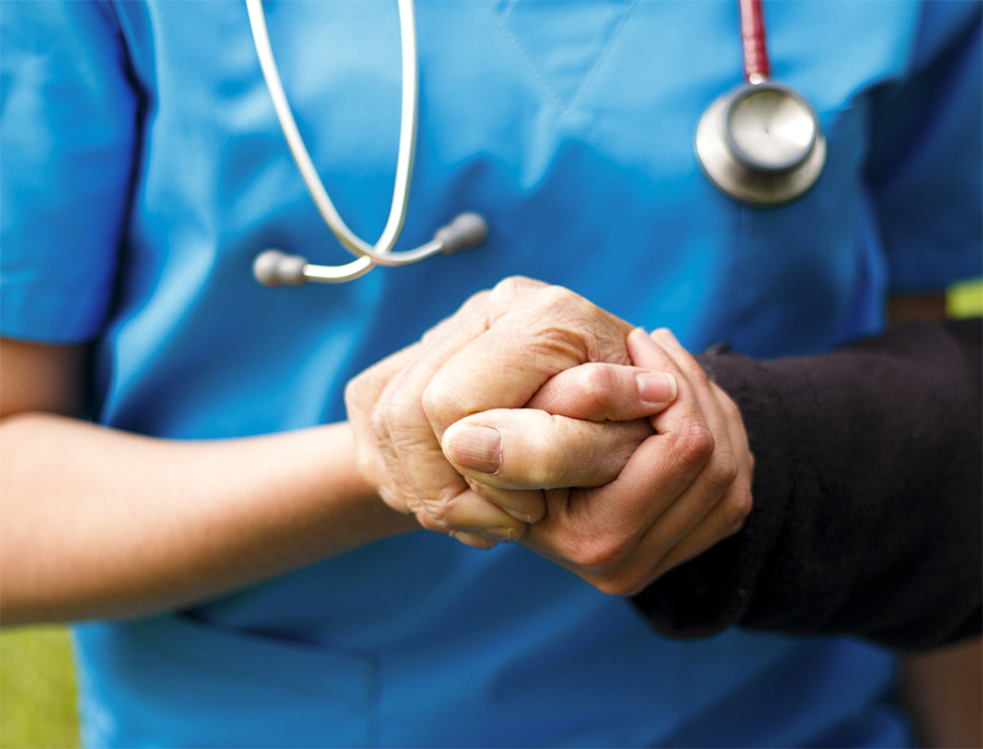 Nurse holding elderly patient's hand 