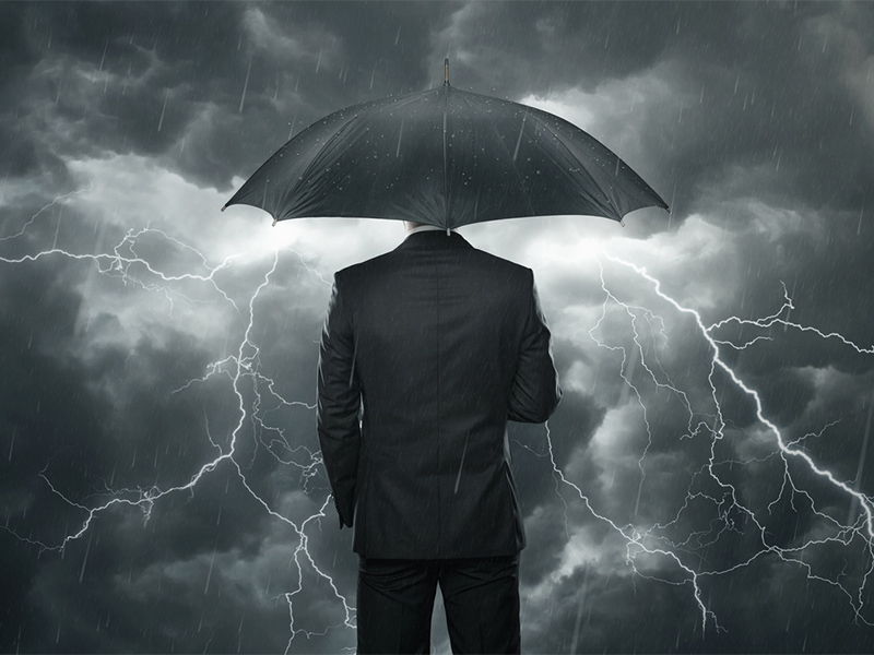 Business man under umbrella in storm