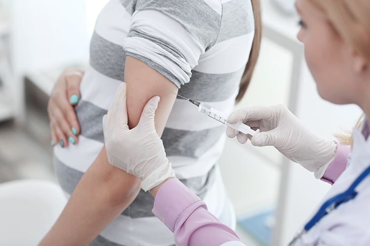 A doctor gives a shot to a pregnant patient